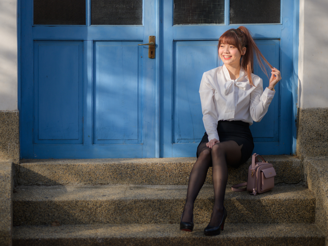 Улыбающаяся азиатка сидит на ступеньках