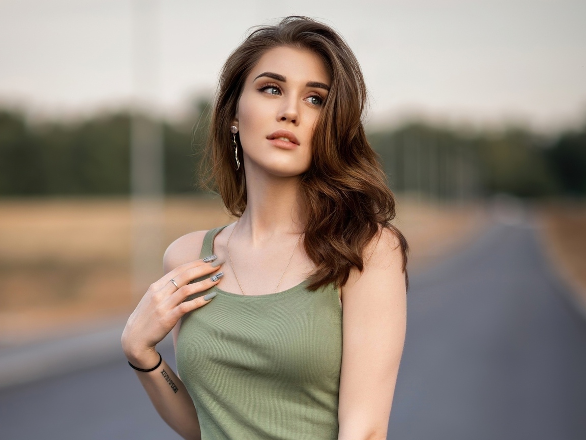 Нежная длинноволосая девушка стоит на дороге