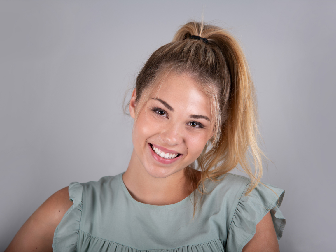 Молодая девушка блондинка на сером фоне