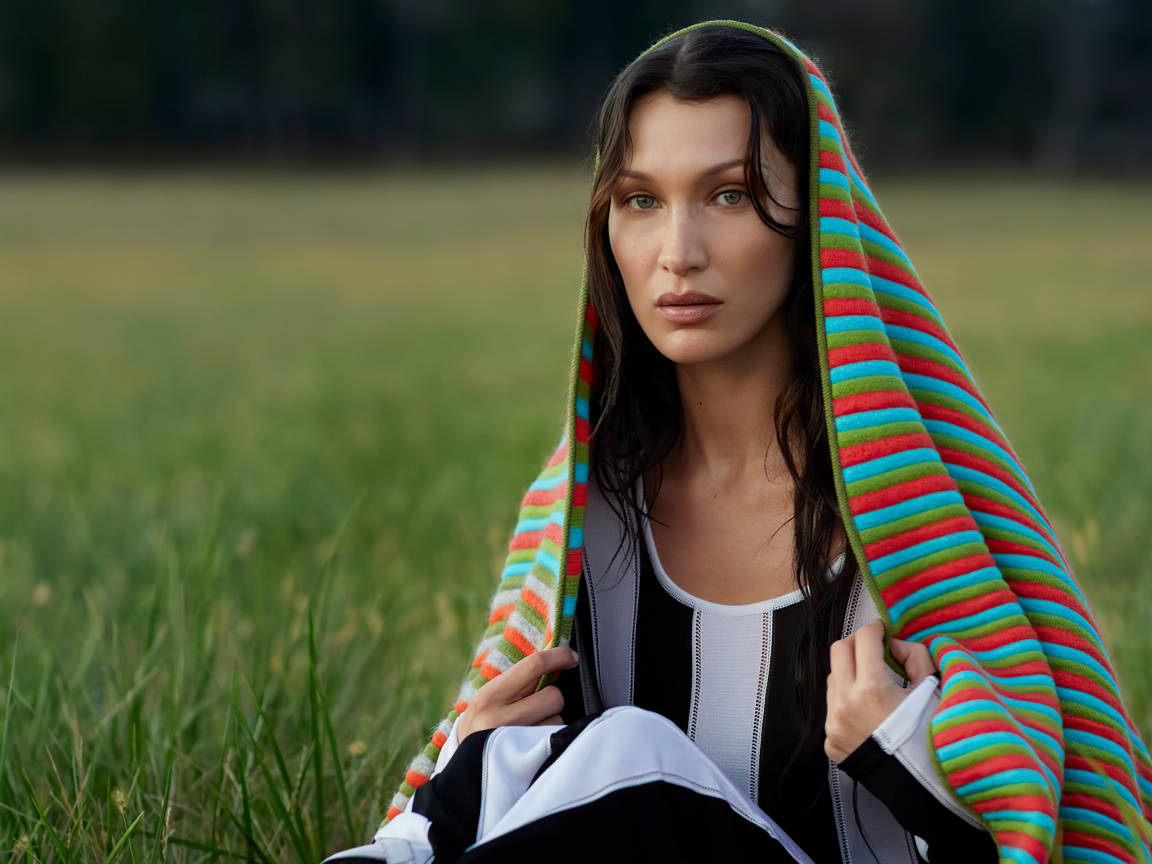 Модель Белла Хадид сидит на траве под пледом