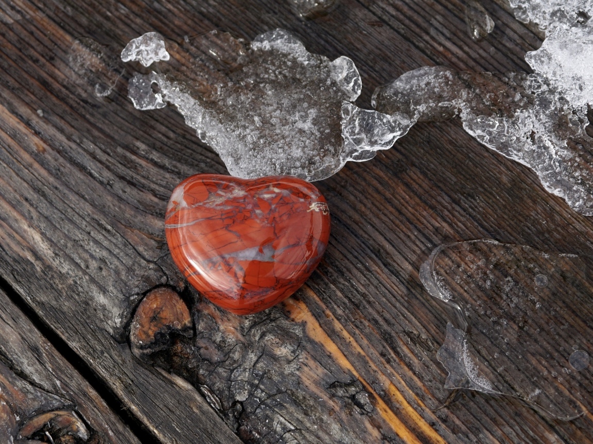 Сердце из камня на деревянной лавке с тающим снегом