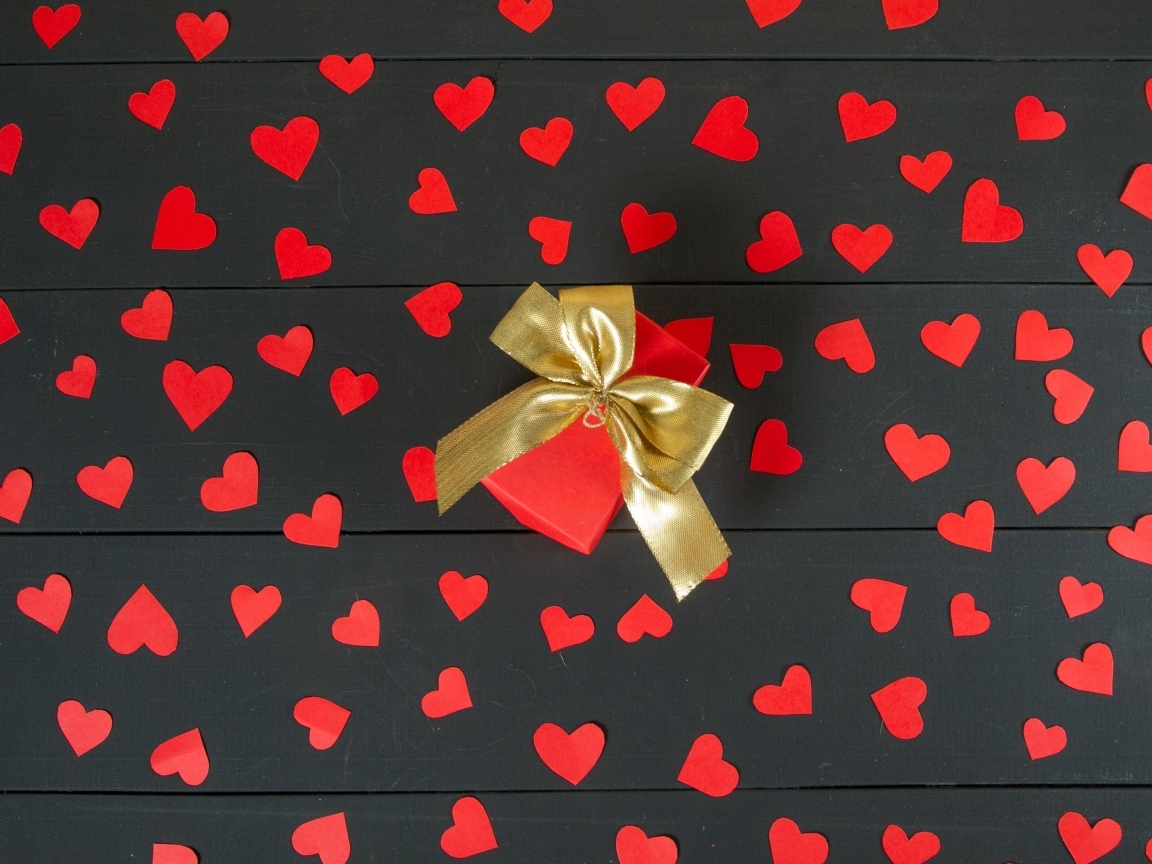 Много маленьких бумажных сердечек с подарком на столе