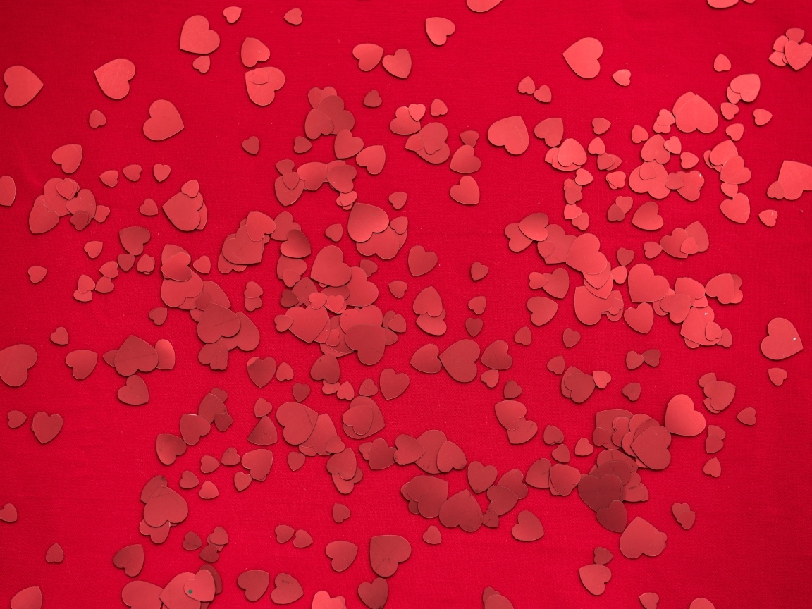 Маленькие бумажные сердечки на красном фоне