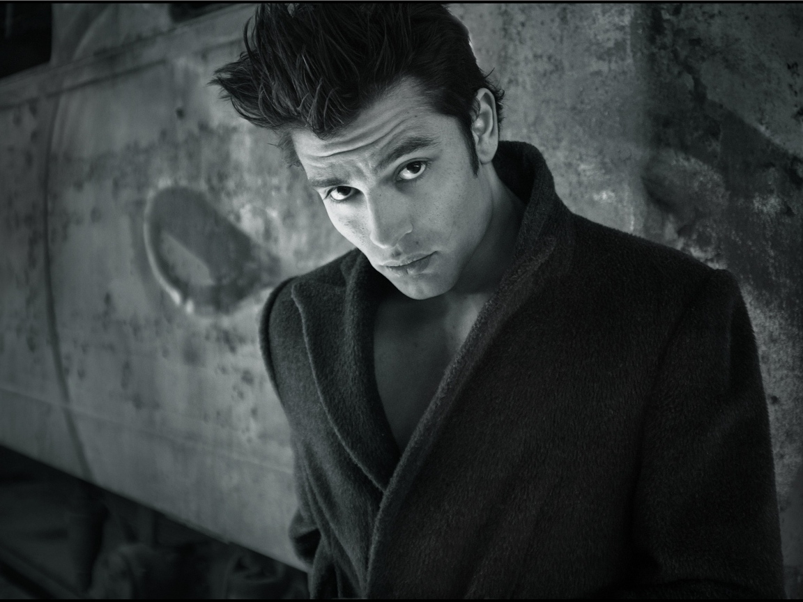 Красивый мужчина в черном пальто у стены