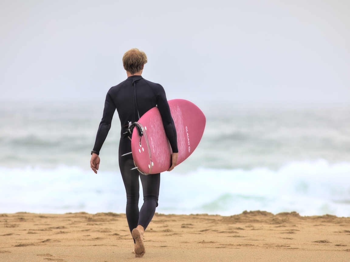 Мужчина серфингист идет к морю