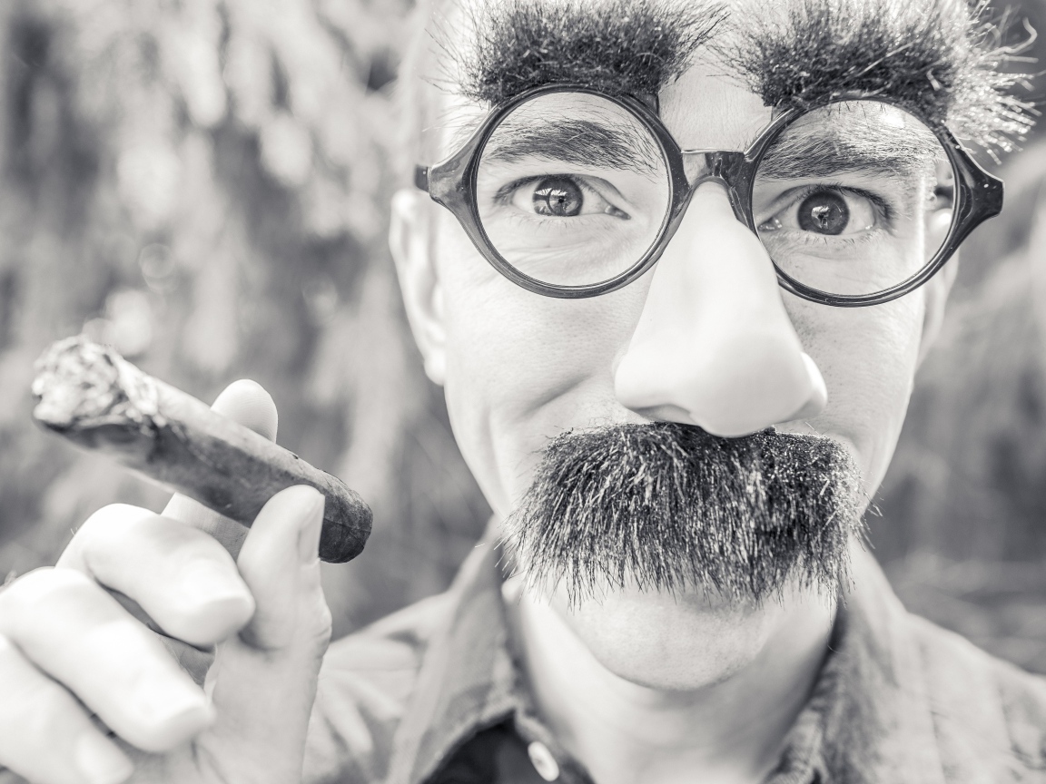 Мужчина в очках с сигарой в руке