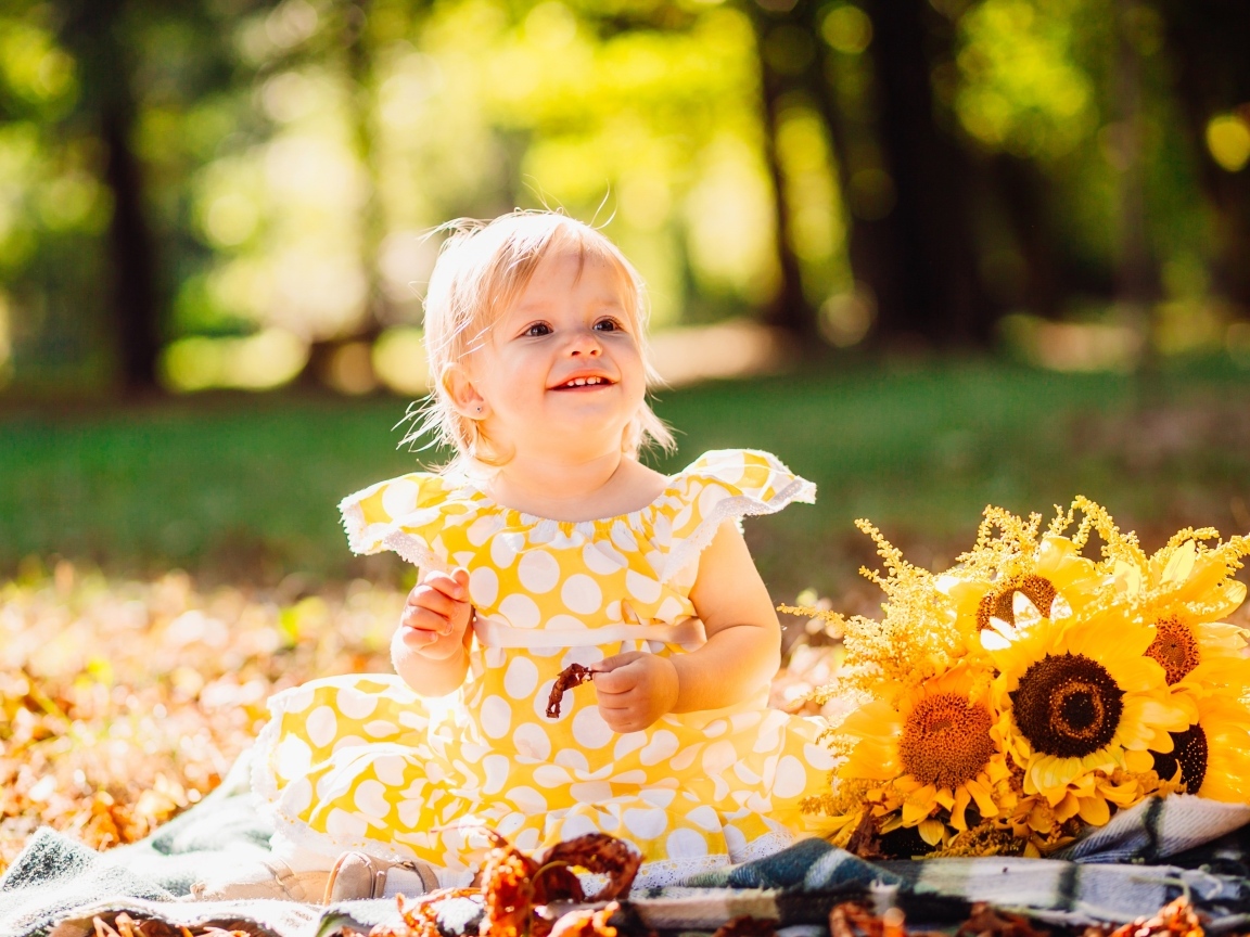 Малышка с цветами подсолнуха на траве