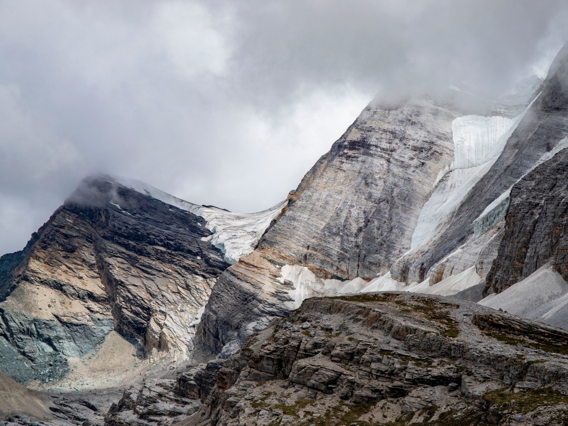 Высокие каменные горы в белых облаках