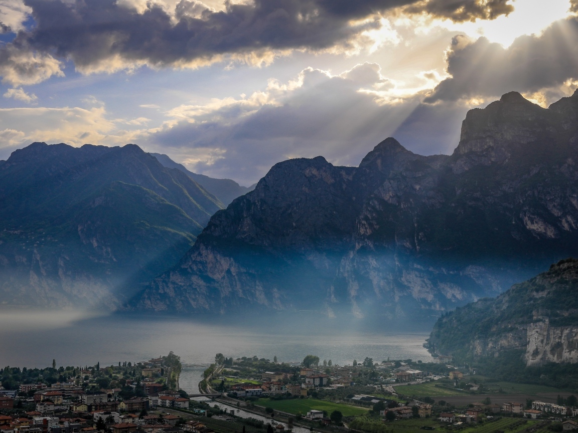 Лучи солнца покрывают горы и город 