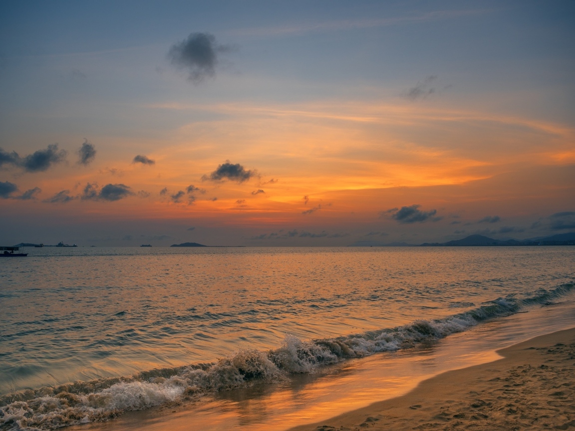 Морские волны омывают берег на закате