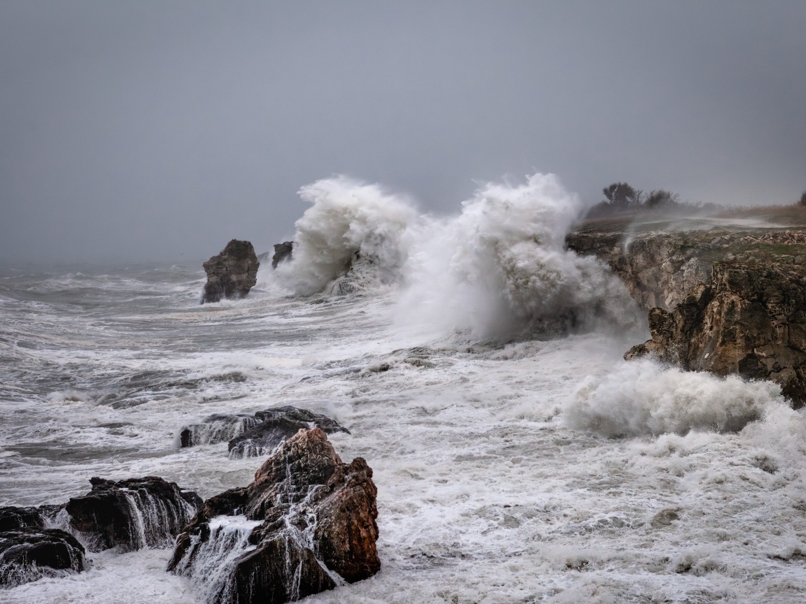 Белые пенные волны бьются об камни во время шторма