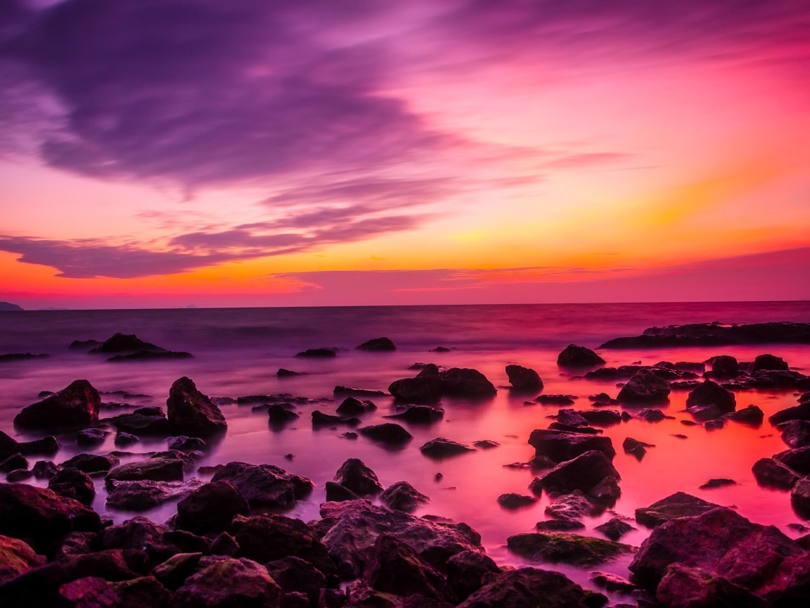 Розовый закат на каменном берегу моря