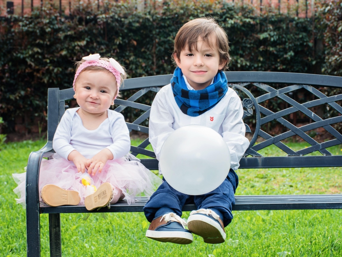 Мальчик и девочка сидят на лавке в парке