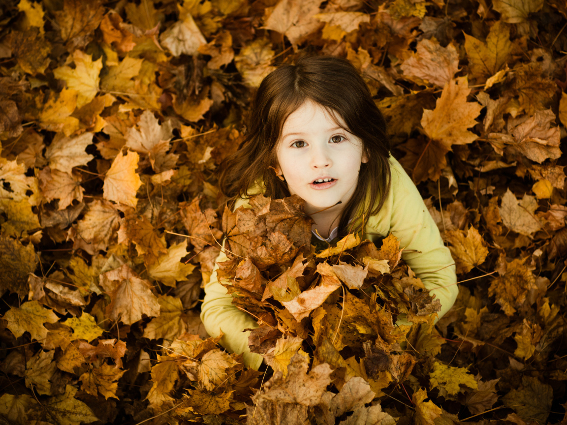 Девочка сидит в опавшей листве