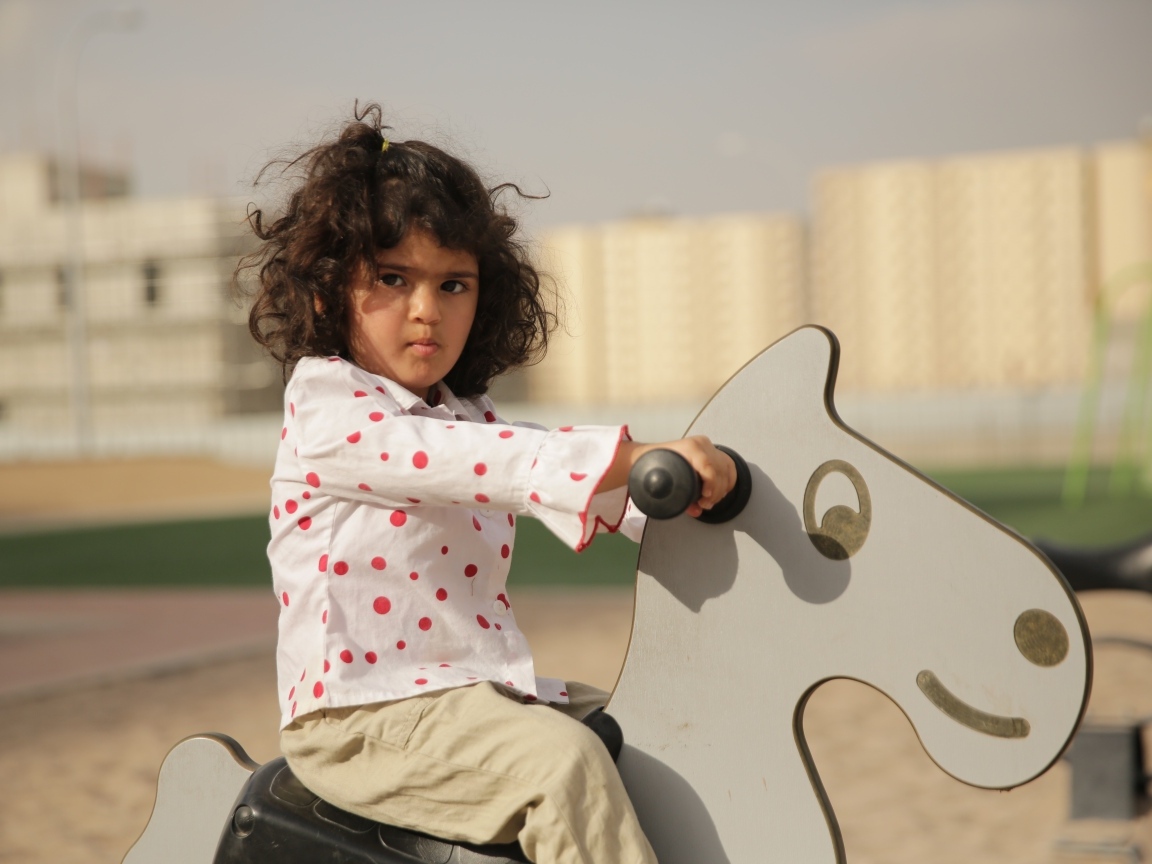 Маленькая девочка на деревянной лошади