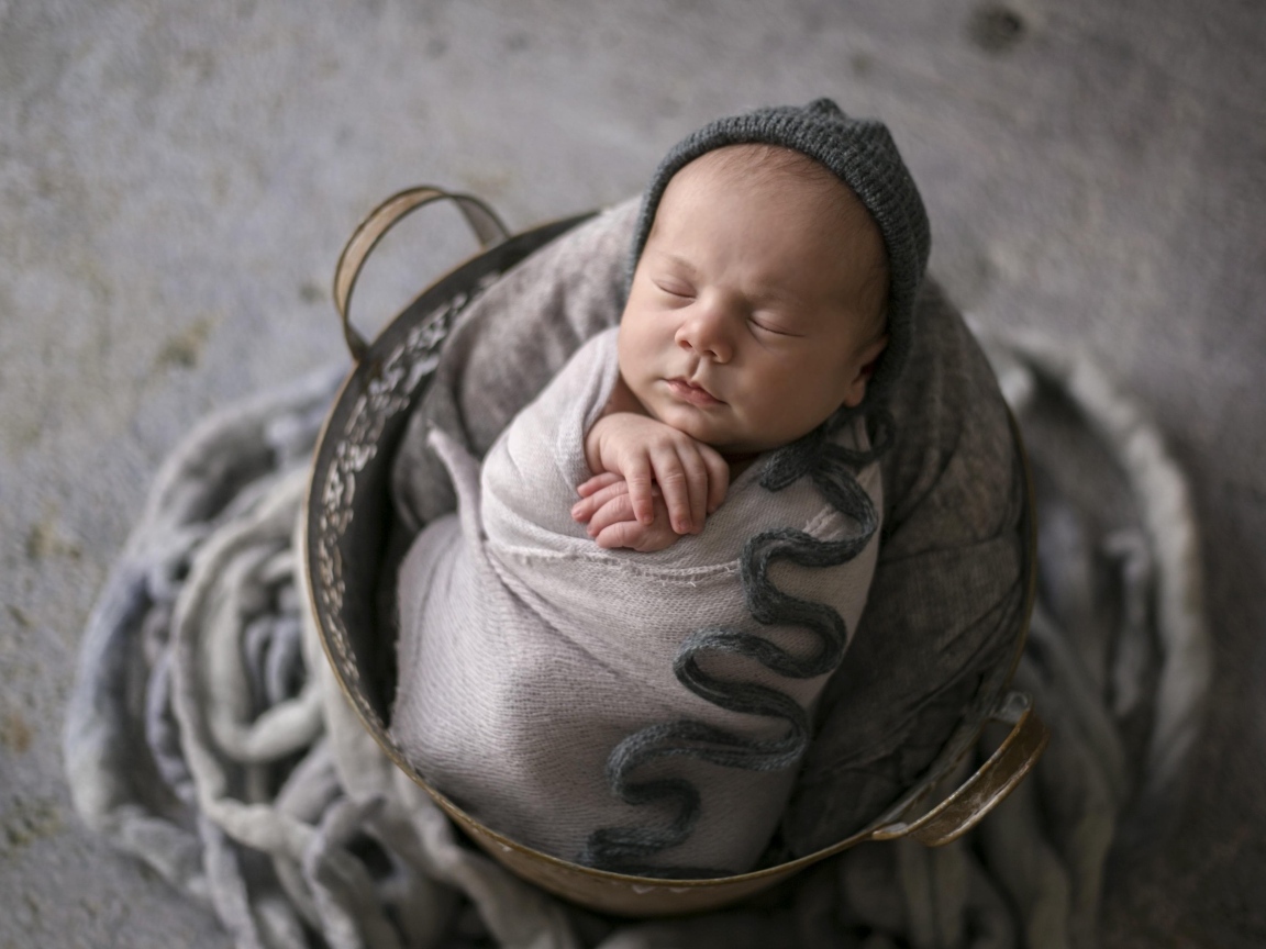 Маленький спящий новорожденный малыш в корзине