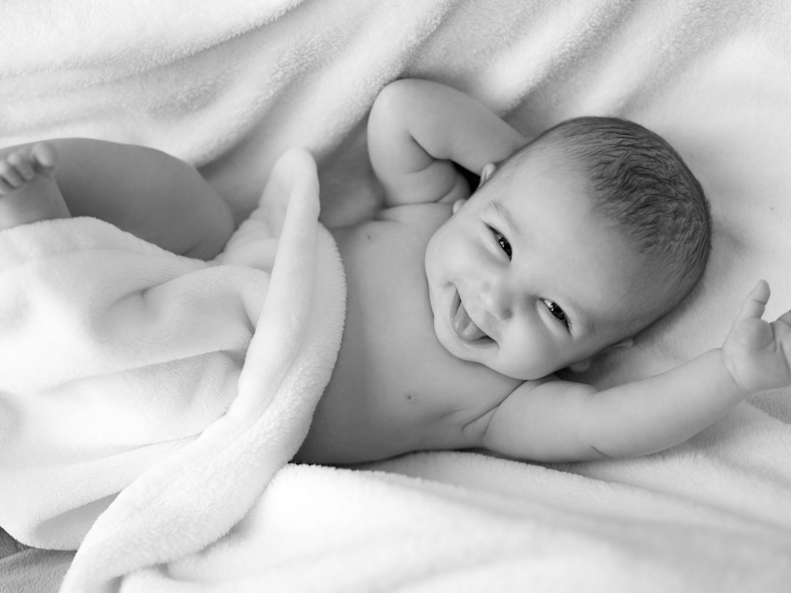 Маленький улыбающийся ребенок в белом покрывале