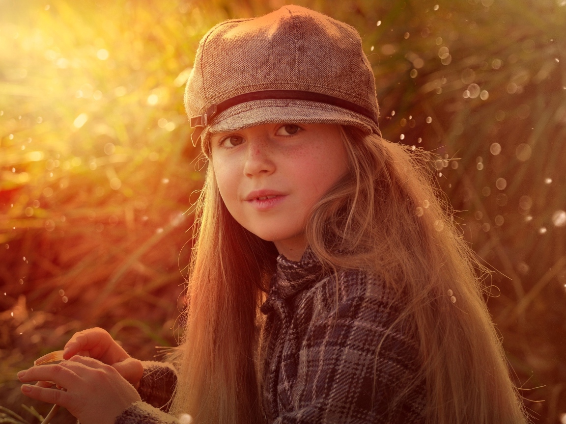 Длинноволосая девочка в кепке в лучах солнца