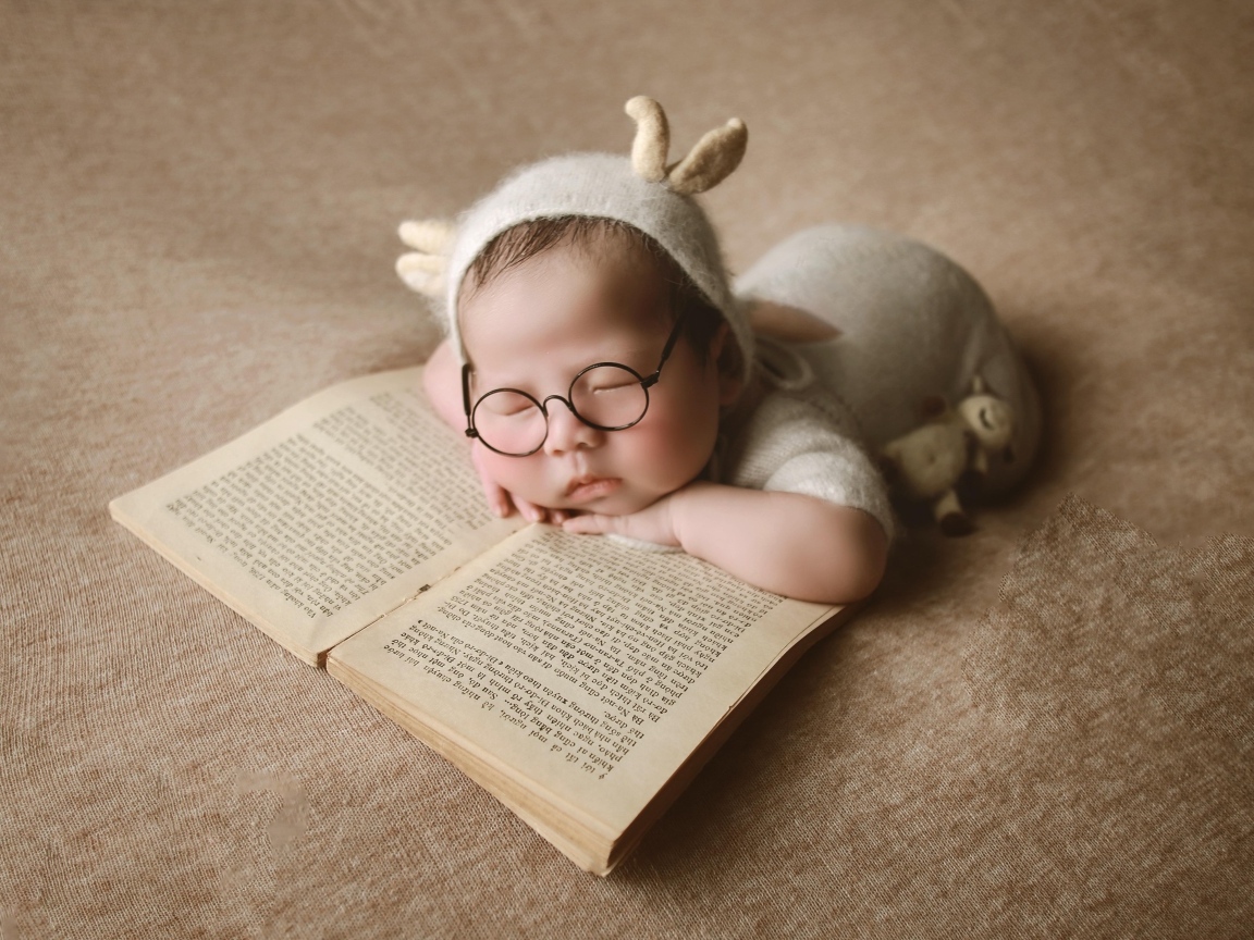 Новорожденный ребенок спит с книгой