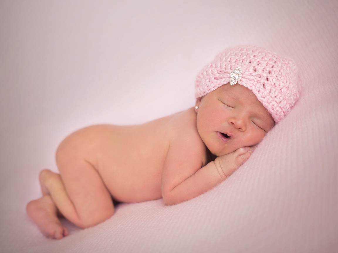 Розовая шапка на голове новорожденной девочки
