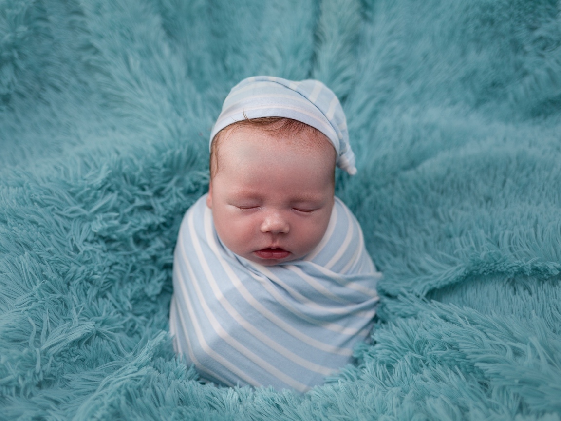 Спящий новорожденный малыш на голубом покрывале 
