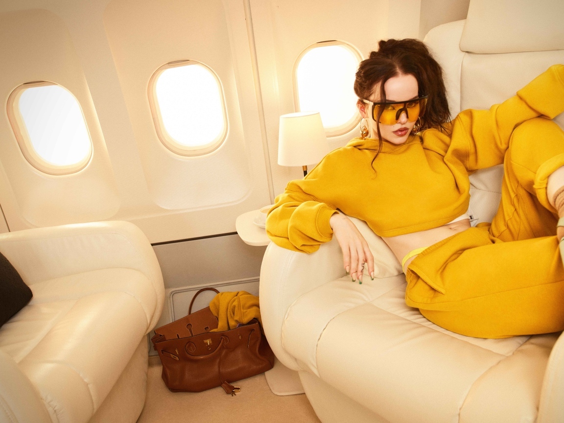 Актриса Дав Кэмерон в желтом костюме в самолете