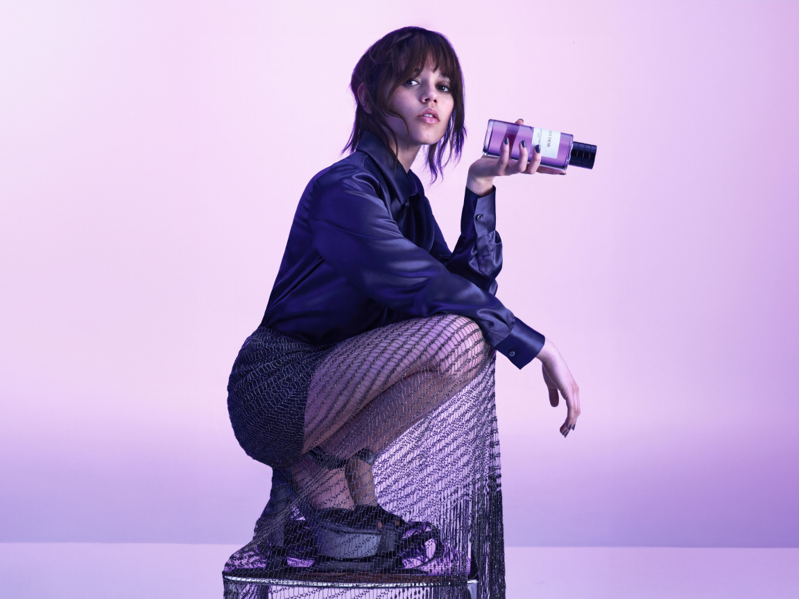 Актриса Дженна Ортега на стуле с духами в руках