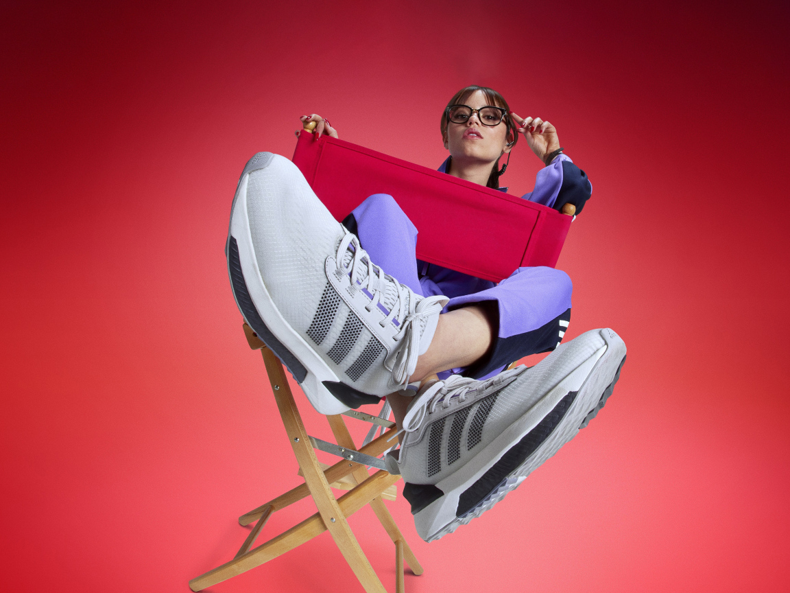 Актриса Дженна Ортега в кроссовках адидас сидит на стуле