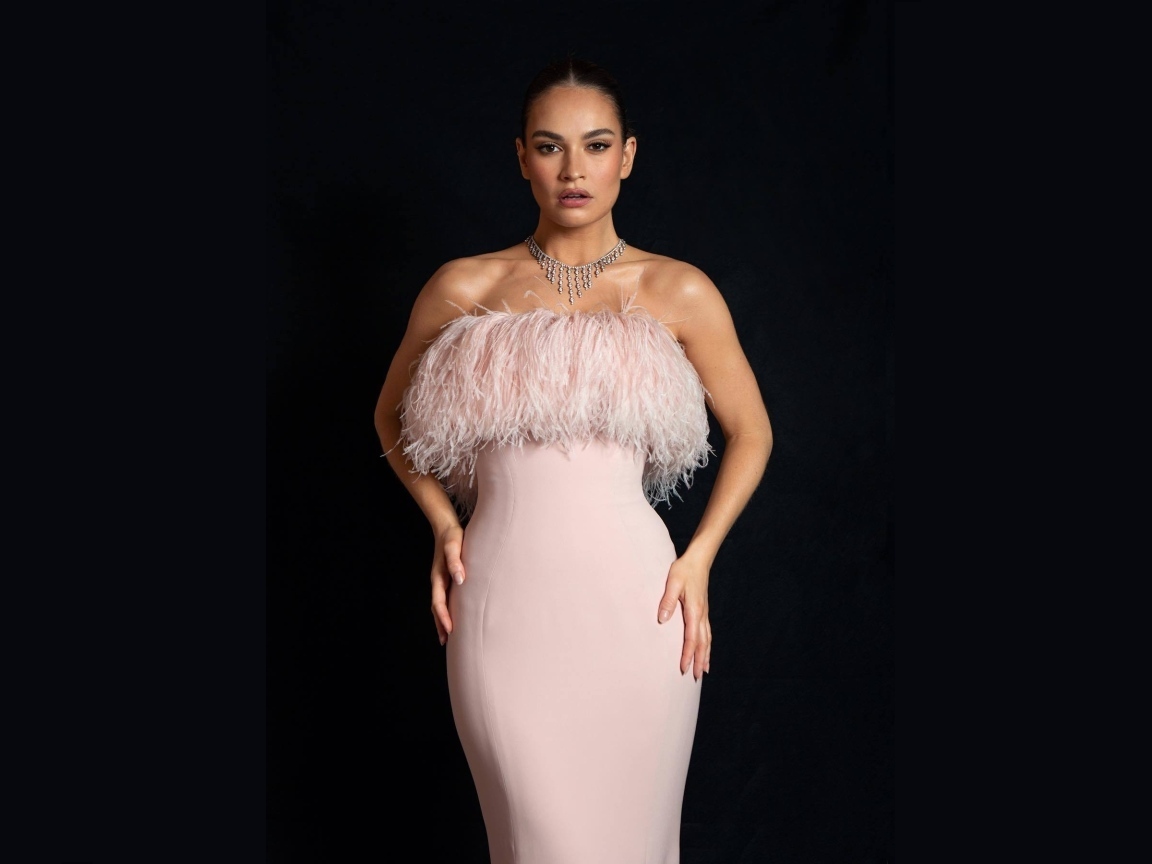 Актриса Лили Джеймс в розовом платье на черном фоне