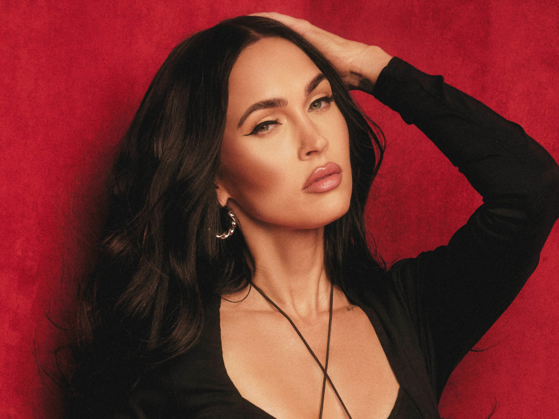 Красивая  Меган Фокс в черном платье у красной стены