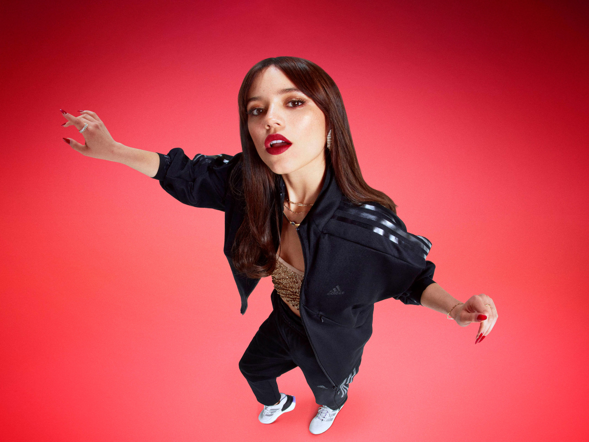 Молодая девушка актриса Дженна Ортега в спортивном костюме на красном фоне