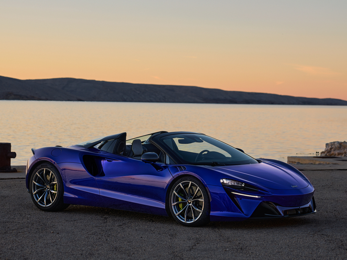 Синий быстрый автомобиль McLaren Artura Spider у воды
