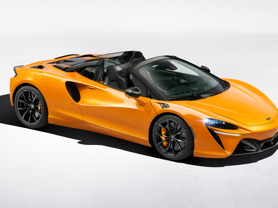 Оранжевый автомобиль McLaren Artura Spider на сером фоне
