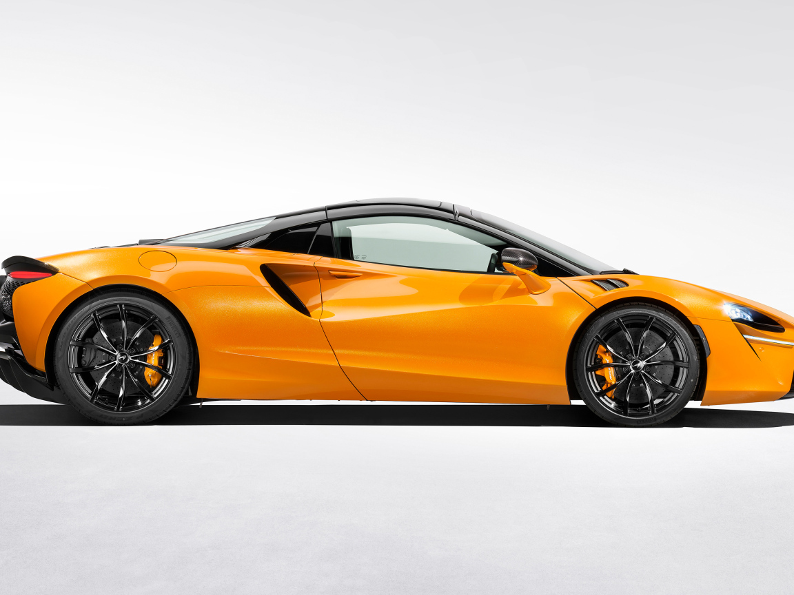 Вид сбоку на оранжевый автомобиль McLaren Artura Spider на белом фоне