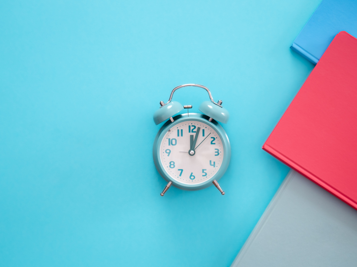 Будильник с книгами на голубом фоне