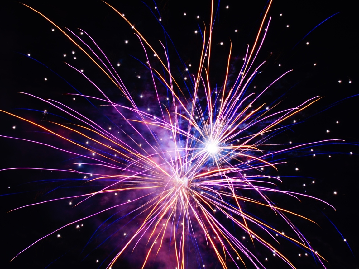 Разноцветные сиреневые искры фейерверка на черном фоне