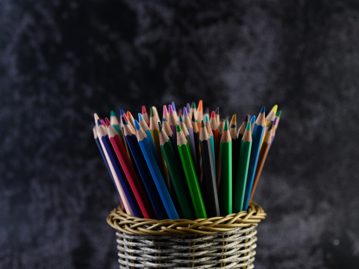 Разноцветные карандаши в стакане на сером фоне