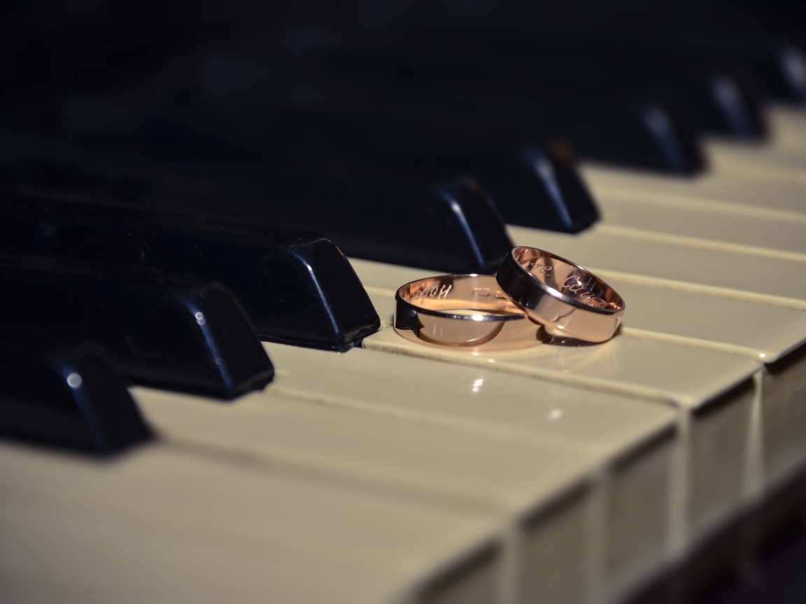 Два золотых обручальных кольца на клавишах пианино 