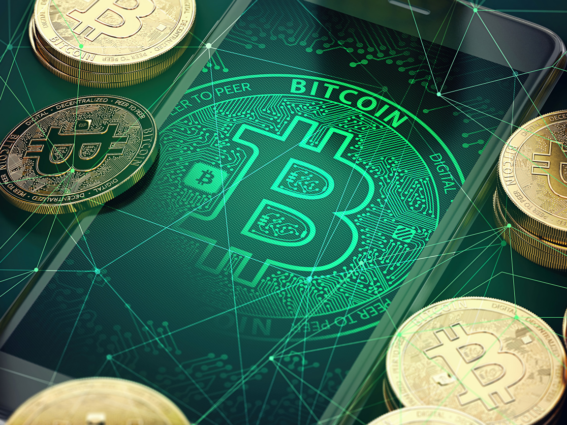 Золотые монеты биткоин со смартфоном на столе