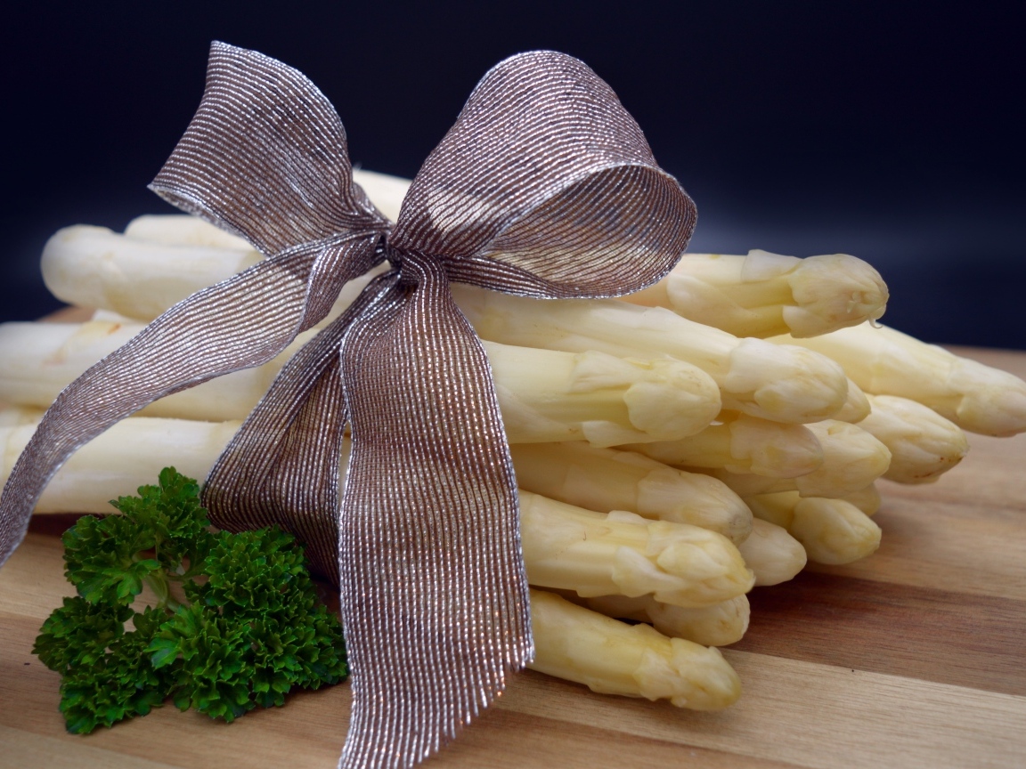 Спаржа с бантом на столе с петрушкой