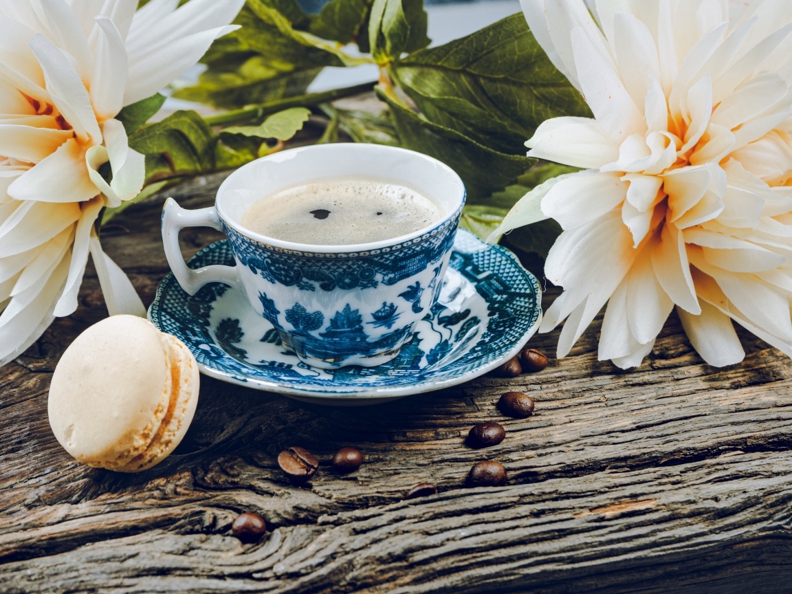 Чашка кофе с макарунами на столе с цветами