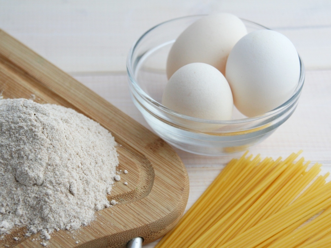 Яйца на столе с мукой и спагетти