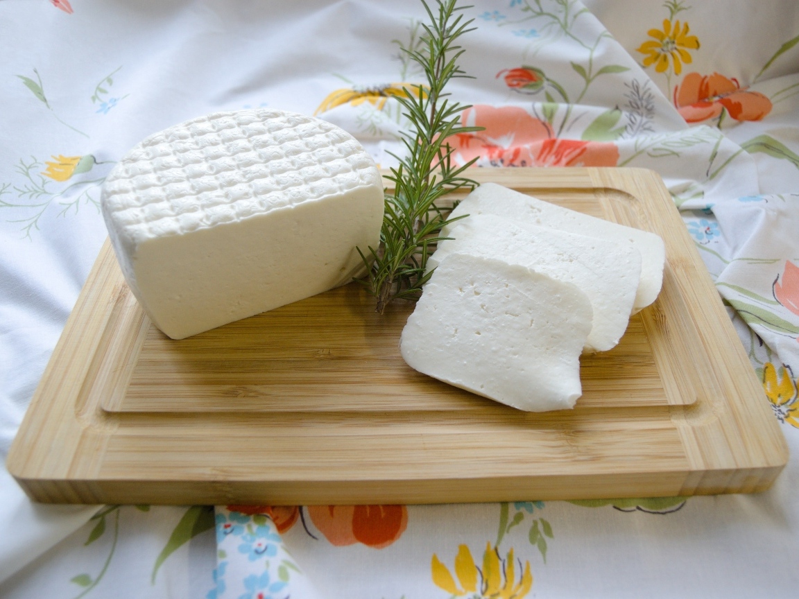 Кусок сыра с розмарином на разделочной доске