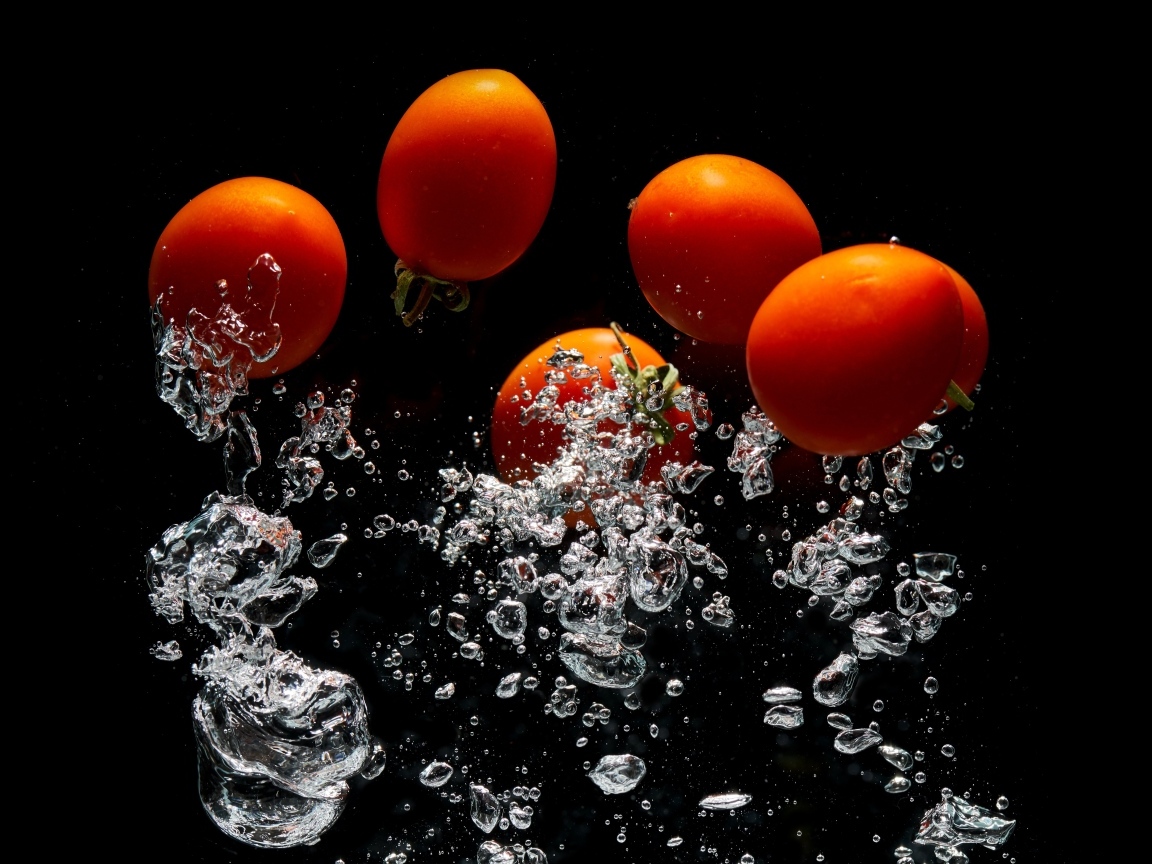 Красные помидоры в воде на черном фоне