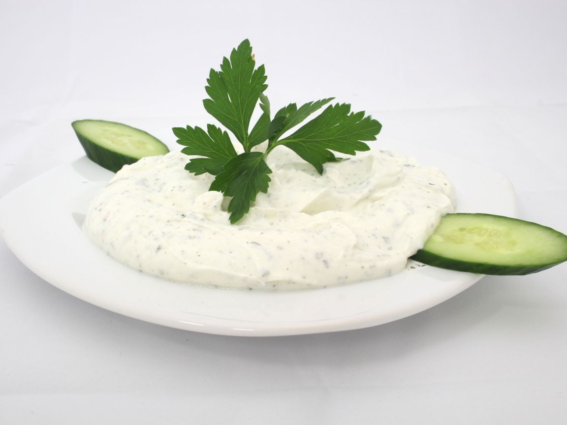 Соус на тарелке со свежими огурцами