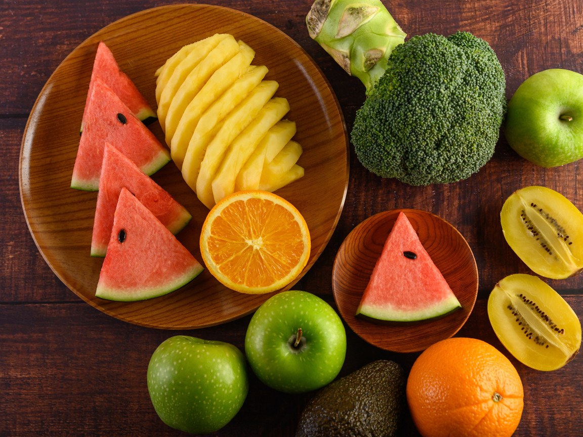 Фрукты и брокколи на столе с доской