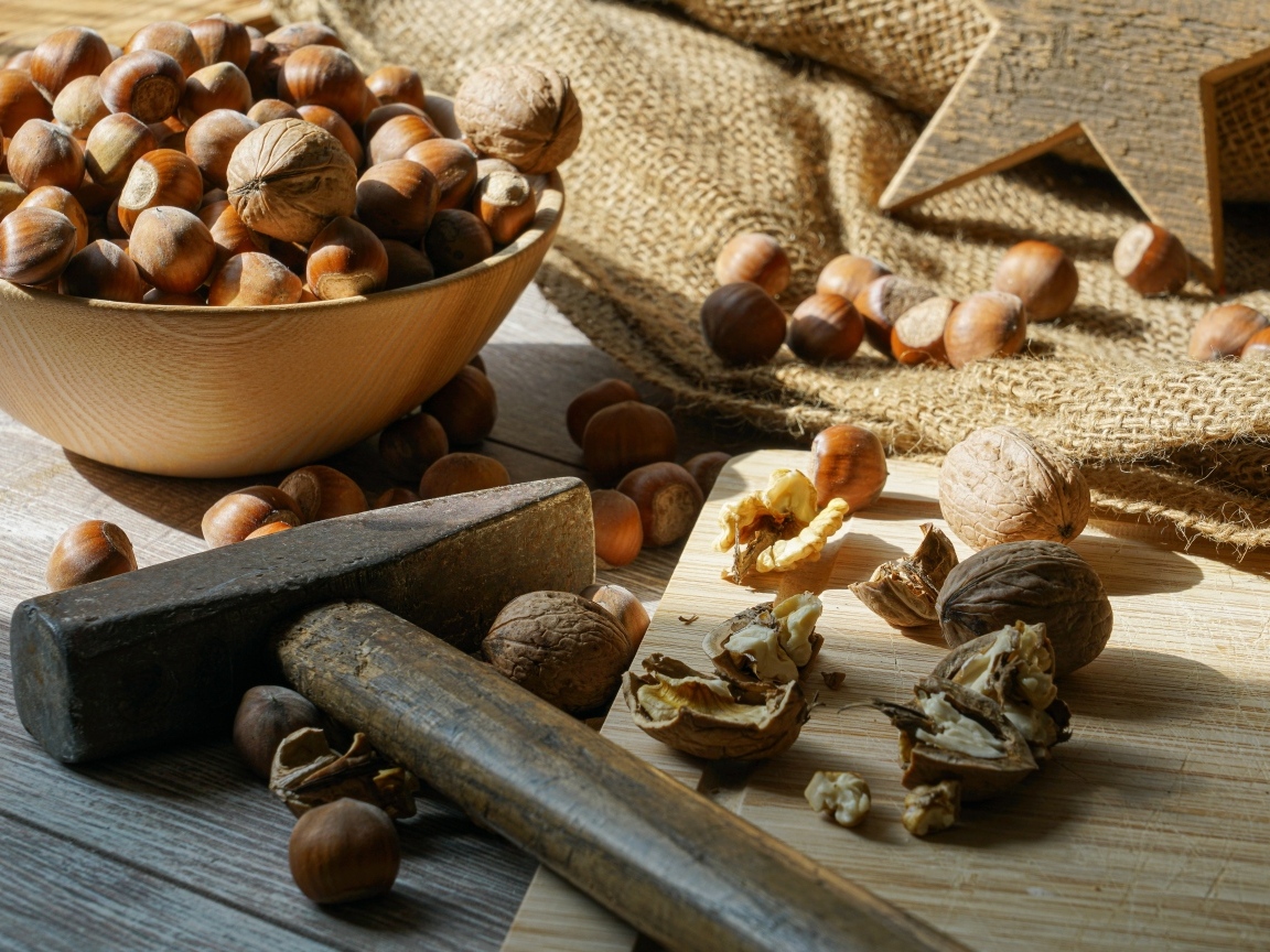 Фундук и грецкие орехи на столе с молотком