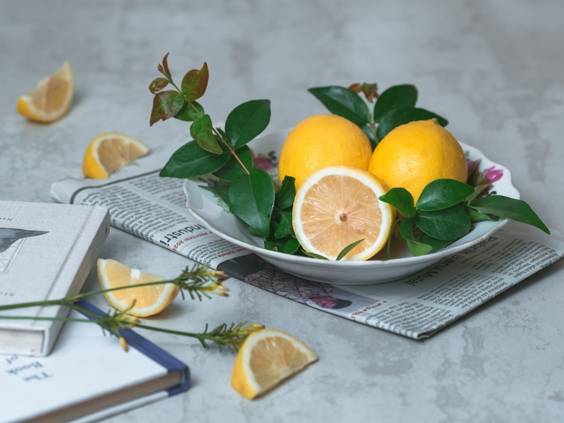 Лимоны на тарелке с зелеными листьями