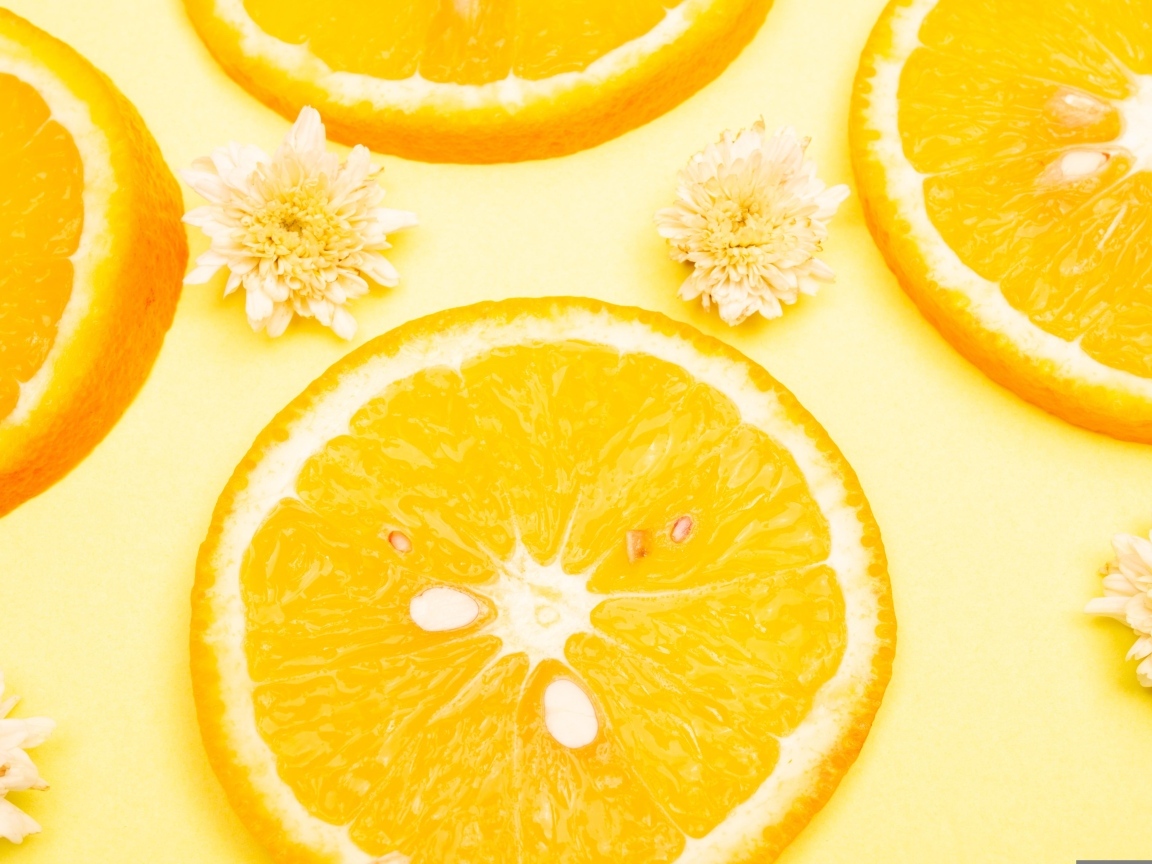 Апельсин с цветами хризантемы на желтом фоне