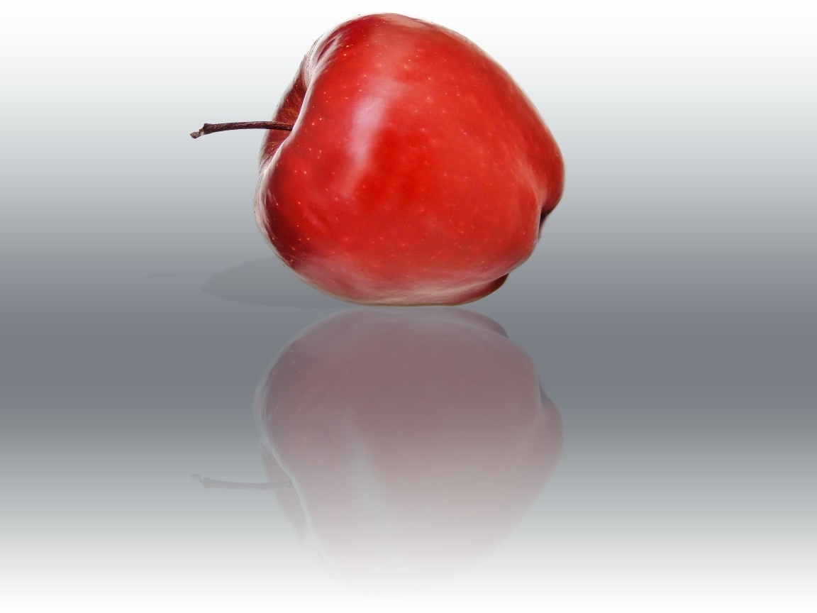 Красное яблоко отражается в серой поверхности